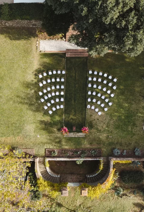 Aerial view of the Villa Lena ceremony lawn with curved rows of white chairs framed by lush greenery.