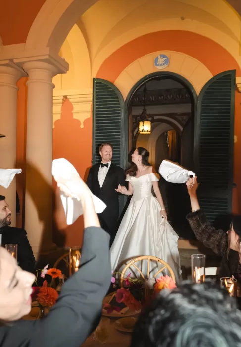 The couple enters their Villa Lena reception holding hands as guests cheer and wave their napkins.
