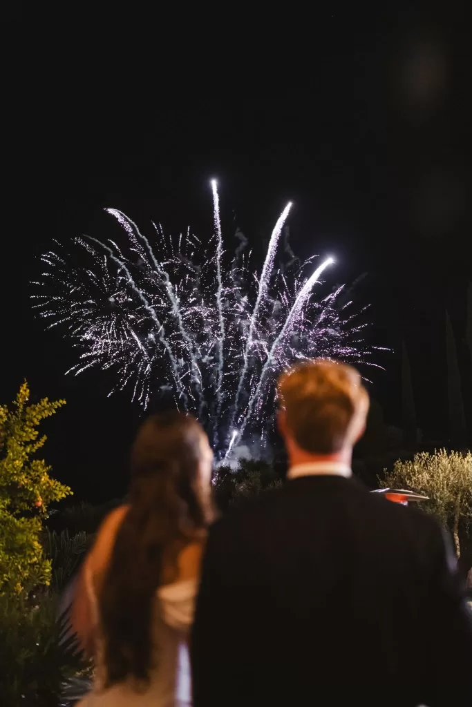 A couple watches a burst of purple fireworks light up the night sky at Villa Lena.