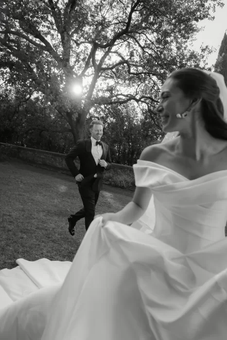 A candid, playful moment as the groom runs toward the bride across the lawn at Villa Lena.
