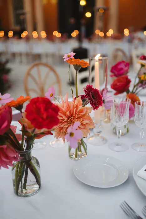 Bright pink and orange floral arrangements decorate the Villa Lena reception tables set with candlelight and glassware.