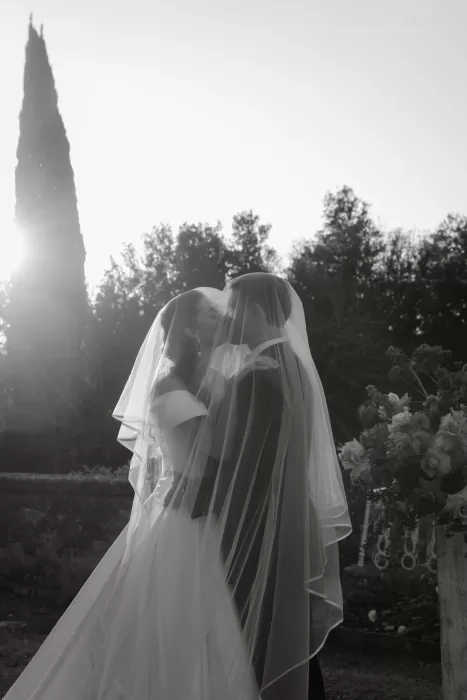 A romantic moment as the couple kisses beneath the bride’s veil with golden light behind them at Villa Lena.