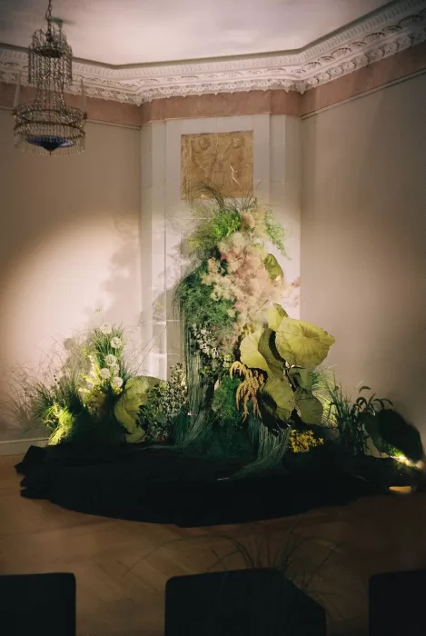 Dramatic floral installation used as wedding décor, blending sculptural greenery and atmospheric lighting in a contemporary space.