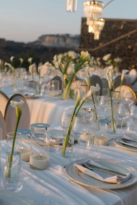 Close-up of candlelit reception table styling at Cavo Ventus, featuring calla lilies, glassware and soft evening light.