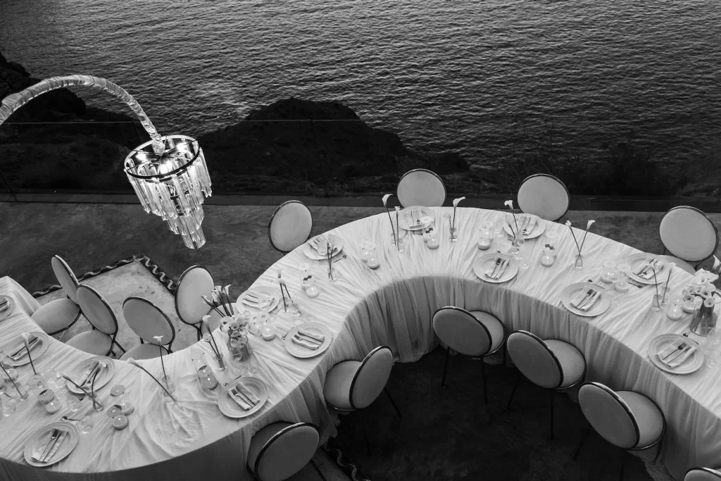 Overhead view of curved reception tables at Cavo Ventus, styled with white linens, candles and floral details beside the sea.