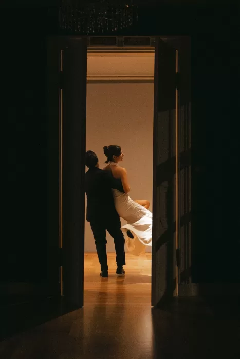 Editorial wedding portrait capturing a couple in motion as they move through a doorway, creating a cinematic and intimate moment.