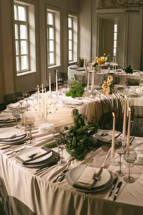 Elegant wedding reception with long tables, candlelight, and soft florals inside a refined historic interior.