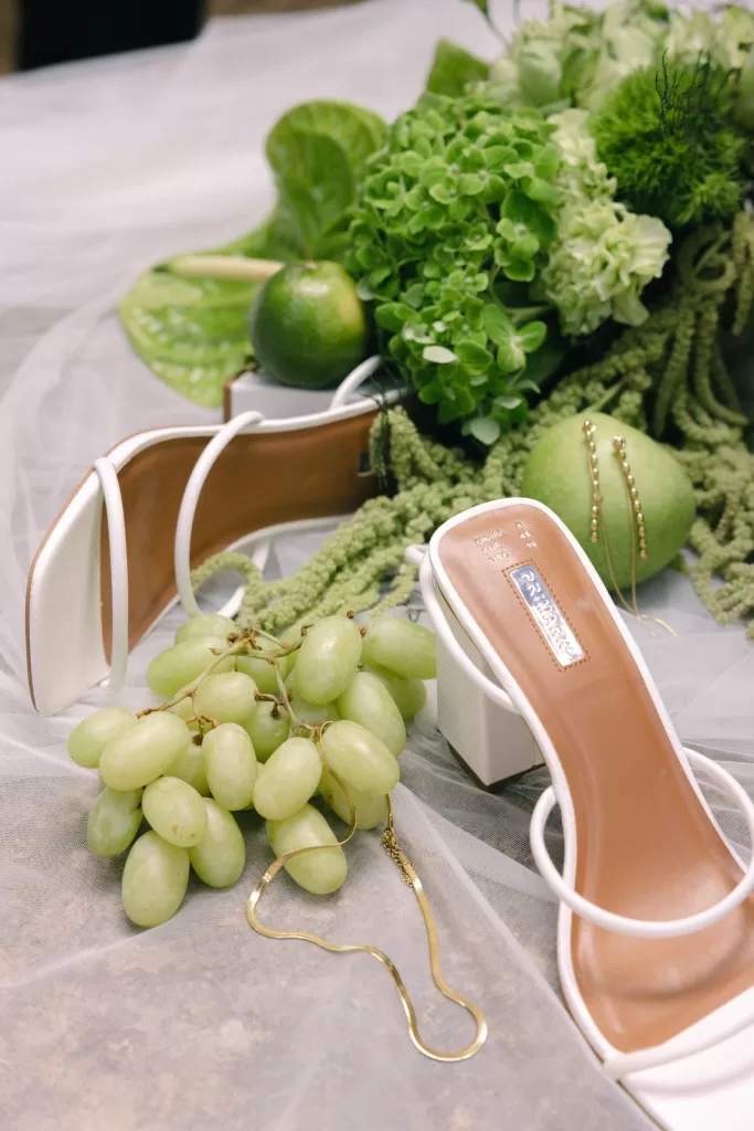 Bridal shoes styled with green florals and fruit details, reflecting the natural palette of a wedding at Finca Es Convent.