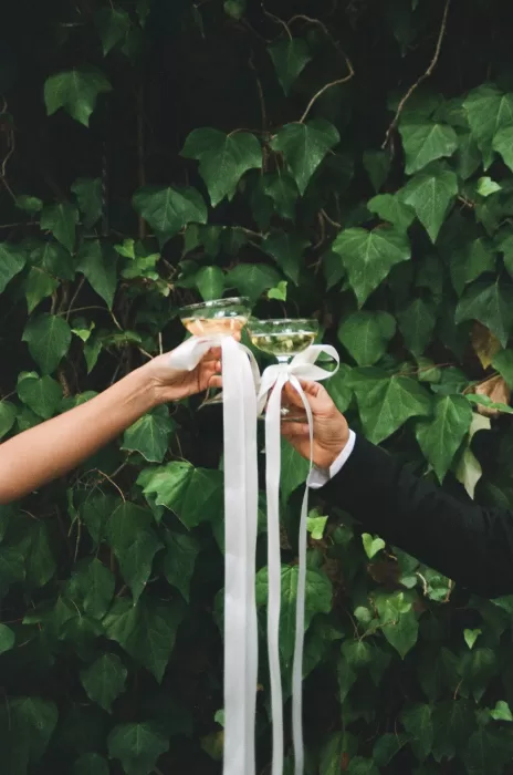 Wedding toast with coupe glasses tied in ribbon, set against ivy-covered walls at Finca Es Convent.