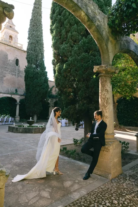 Bride and groom sharing a quiet moment beneath stone arches in the courtyard at Finca Es Convent.
