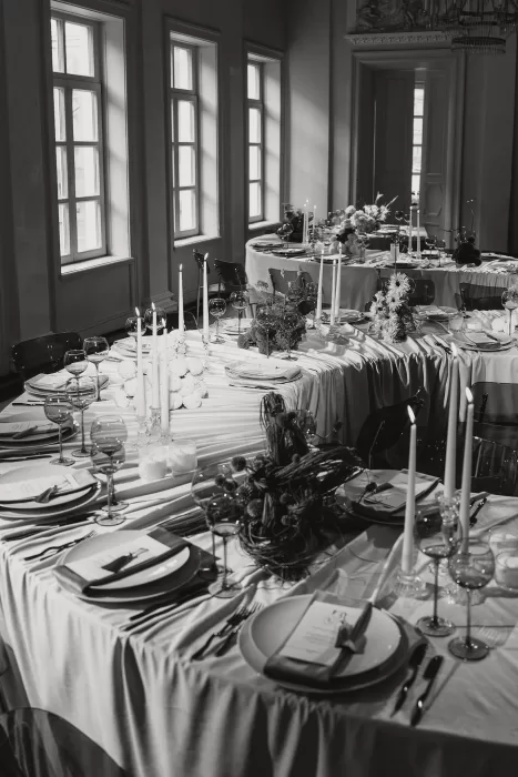Elegant fine art wedding reception with candlelit tables, floral arrangements, and natural daylight streaming through tall windows.