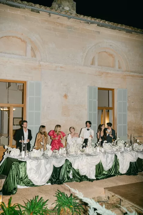 Wedding party gathered at the head table at Fontsanta during the evening reception with candlelight and green draping.