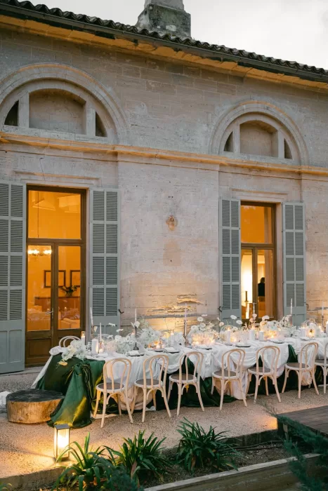 Evening wedding reception table at Fontsanta with glowing candles, bentwood chairs and soft lighting outside the villa.
