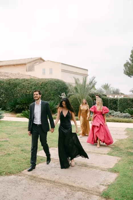 Wedding guests walking through the Fontsanta gardens dressed in elegant eveningwear before the reception.