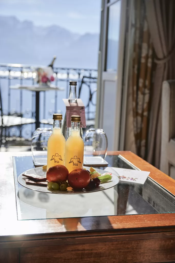 In-room breakfast served on a balcony at Grand Hotel du Lac with lake and mountain views beyond.