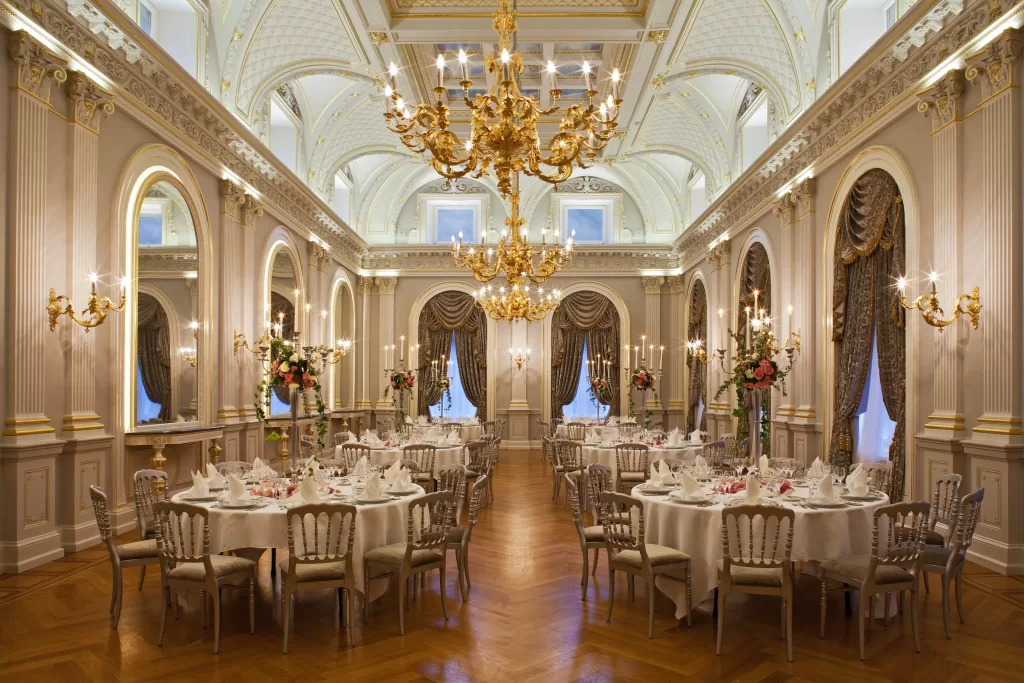 Grand ballroom at Grand Hotel du Lac styled for an elegant wedding dinner with chandeliers, round tables and floral centrepieces.