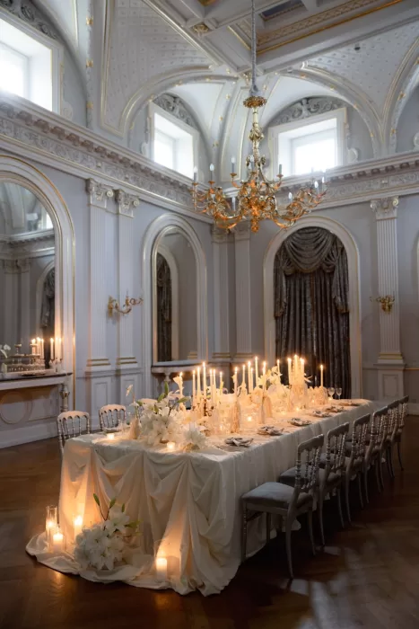 Long wedding table styled with white florals and candlelight beneath chandeliers in the ballroom at Grand Hotel du Lac.