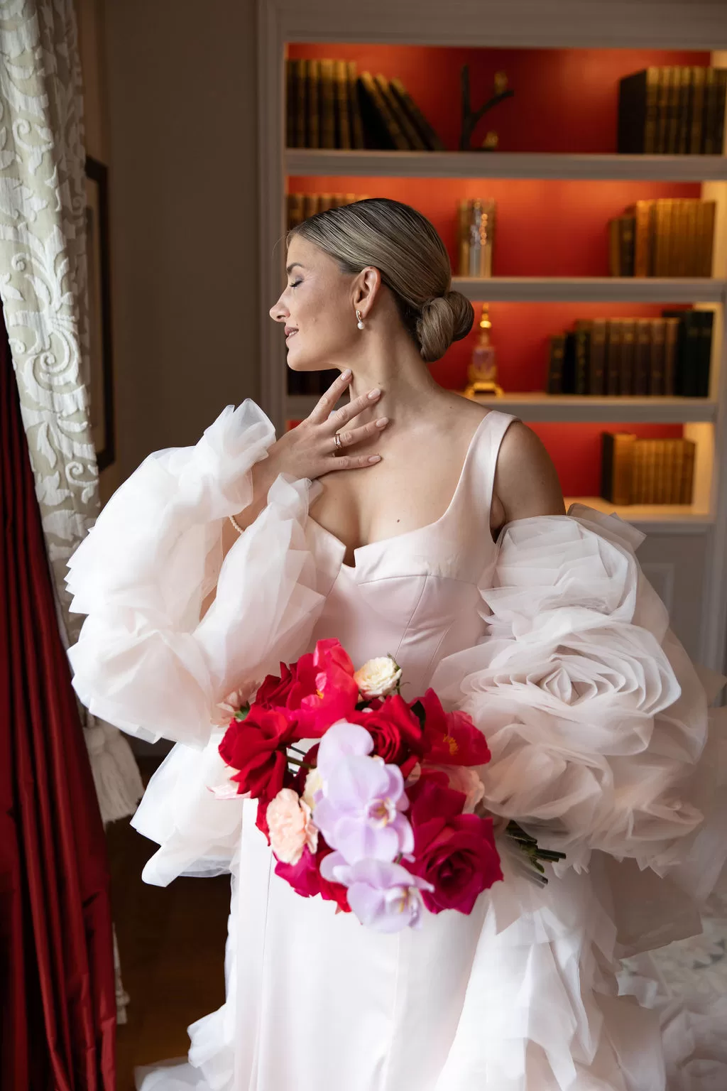Bride holding a vibrant bouquet in an intimate library setting at Grand Hotel du Lac, captured in soft natural light.