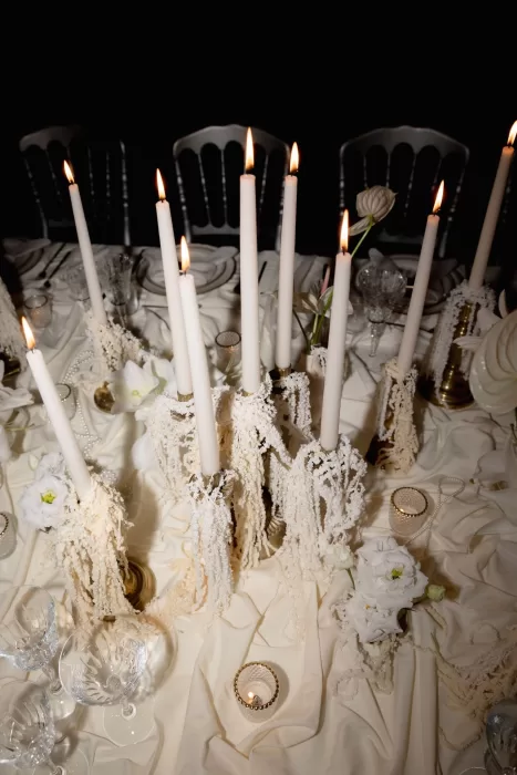 Candlelit wedding table at Grand Hotel du Lac featuring textured linens, tall candles and refined floral details against a dark backdrop.