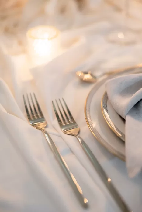 Close-up of elegant cutlery and layered plates on a candlelit wedding table at Grand Hotel du Lac.