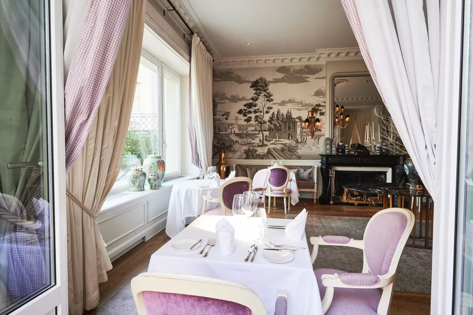 Veranda dining room at Grand Hotel du Lac with white table linens, fireplace and classic decorative details.