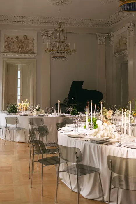 Grand wedding reception room with round tables, candlelit florals, and classical architectural details.