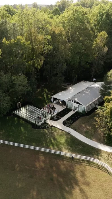 Aerial view of The Greenhouse at Arrows Farm showing the ceremony lawn, greenhouse structure, and surrounding woodland.