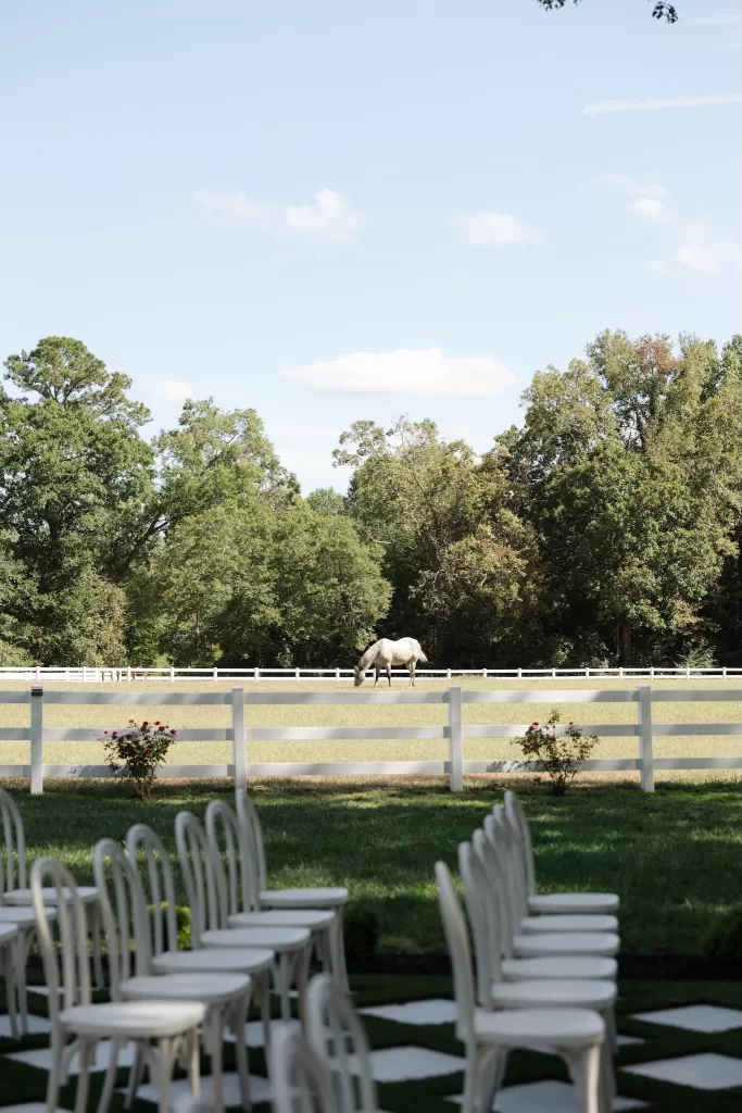 White chairs line the garden ceremony aisle at The Greenhouse at Arrows Farm with open countryside views beyond.