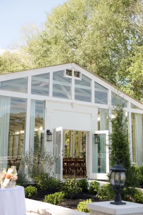 Sunlight reflects off the glass walls of The Greenhouse at Arrows Farm, highlighting its modern white exterior.