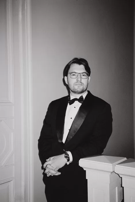 Editorial portrait of a groom in a classic tuxedo, photographed indoors with soft light and a timeless, cinematic feel.