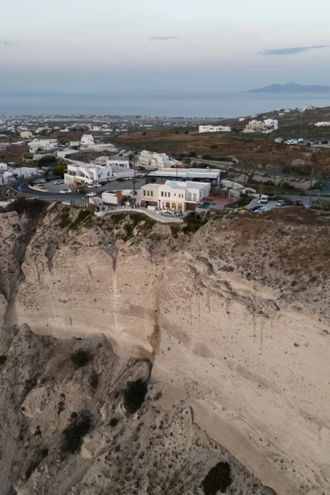 Aerial view of Islet Santorini perched on the cliffs, showcasing the venue’s dramatic location above the sea.