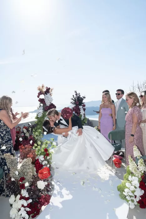 Bride and groom sharing their first kiss during a cliffside wedding ceremony at Islet Santorini.