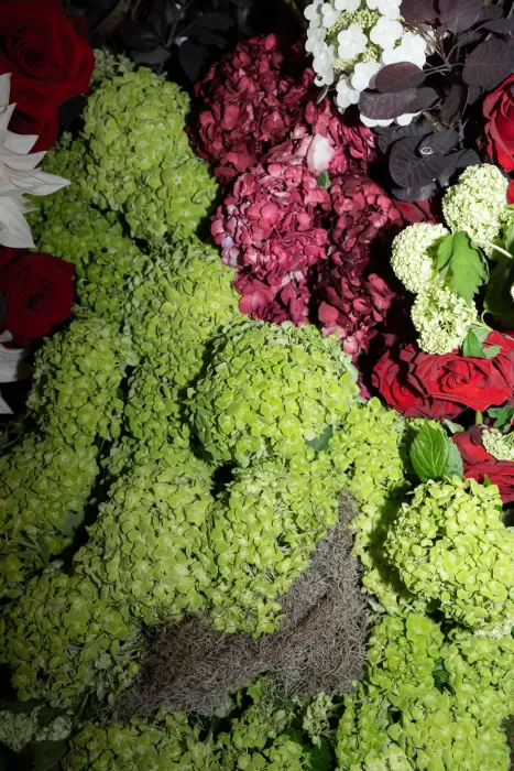 Close-up of rich floral installations in deep red and green tones at a wedding at Islet Santorini.
