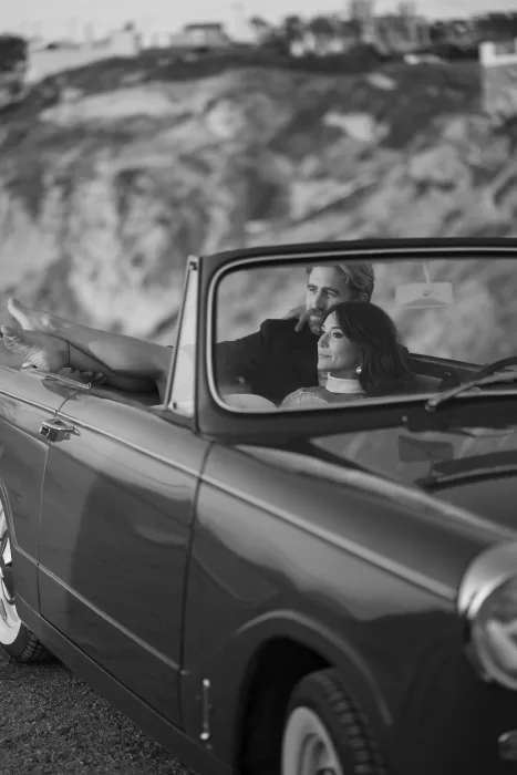 Bride and groom relaxing in a vintage convertible during a wedding photoshoot at Islet Santorini.