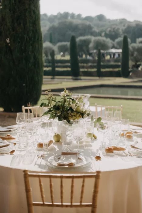 Elegant outdoor reception table set beside the reflecting pools at Mas de Les Voltes, styled with glassware and floral details.