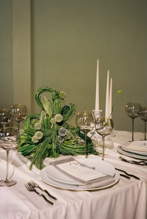 Modern wedding tablescape with sculptural floral design, layered place settings, and soft natural tones.