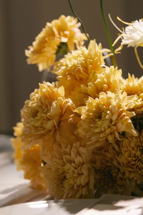 Close-up of yellow wedding florals arranged as a modern tablescape detail, photographed in soft natural light.