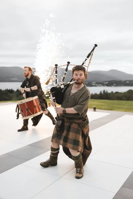 Traditional Scottish bagpipers performing outdoors with Loch Lomond views at Boturich Castle.