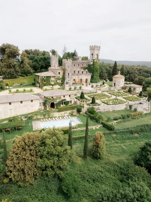 Elevated view of Castello di Celsa with manicured gardens, pool and rolling Tuscan landscape.