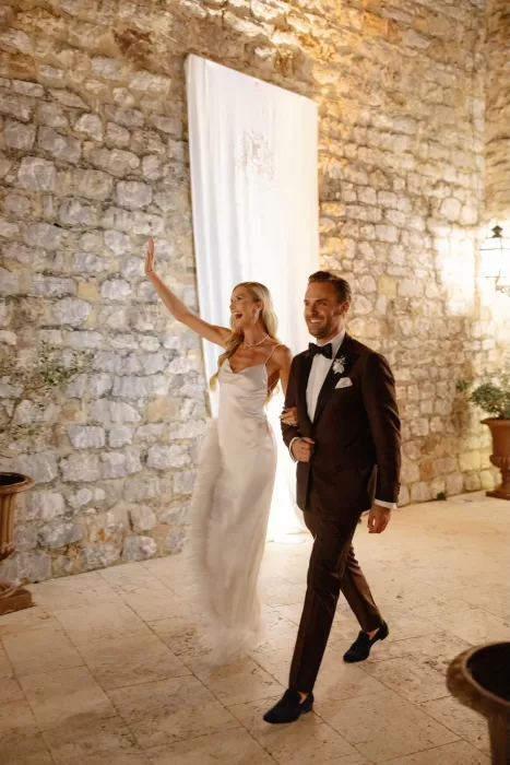 Bride and groom entering evening reception beneath stone walls at Castello di Velona.