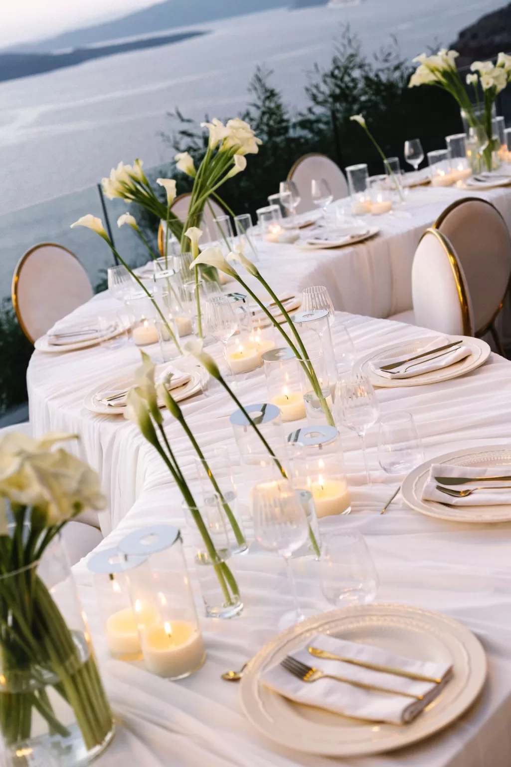 Candlelit wedding reception tables at Cavo Ventus styled with calla lilies, glassware and white linens overlooking the sea.