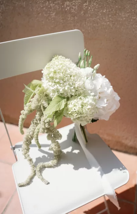 White hydrangea and rose bridal bouquet resting on a chair at Château Canet, styled in soft natural light against warm terracotta tones.