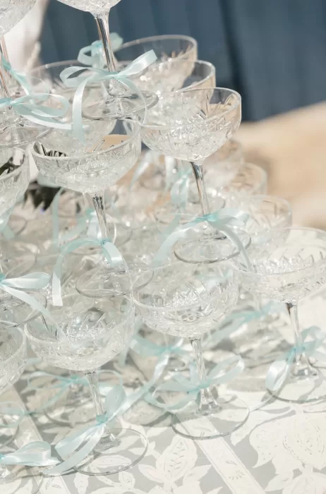 Crystal coupe glasses tied with pale blue ribbons arranged as a champagne tower at Château Canet, adding a romantic and celebratory touch to the reception styling.