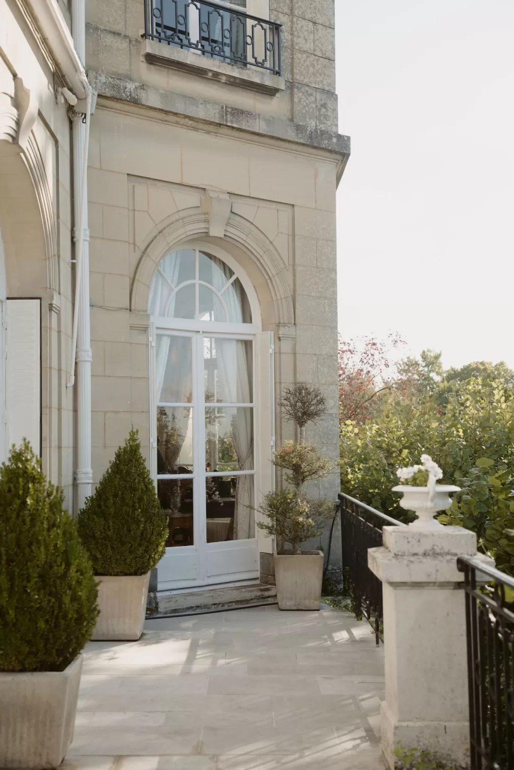 French doors opening onto a small balcony at Château du Prieuré d’Evecquemont, framed by stonework and greenery.