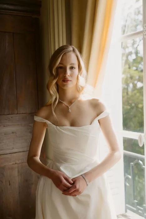 Bridal portrait by the window inside Château du Prieuré d’Evecquemont, highlighting elegance and soft natural light.