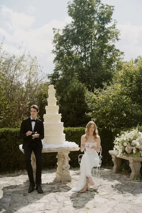Bride and groom enjoying cake together in the garden at Château du Prieuré d’Evecquemont, styled with classic elegance.