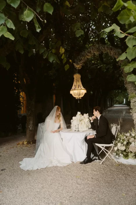 Romantic outdoor dinner setup beneath trees at Château du Prieuré d’Evecquemont, illuminated by a chandelier.