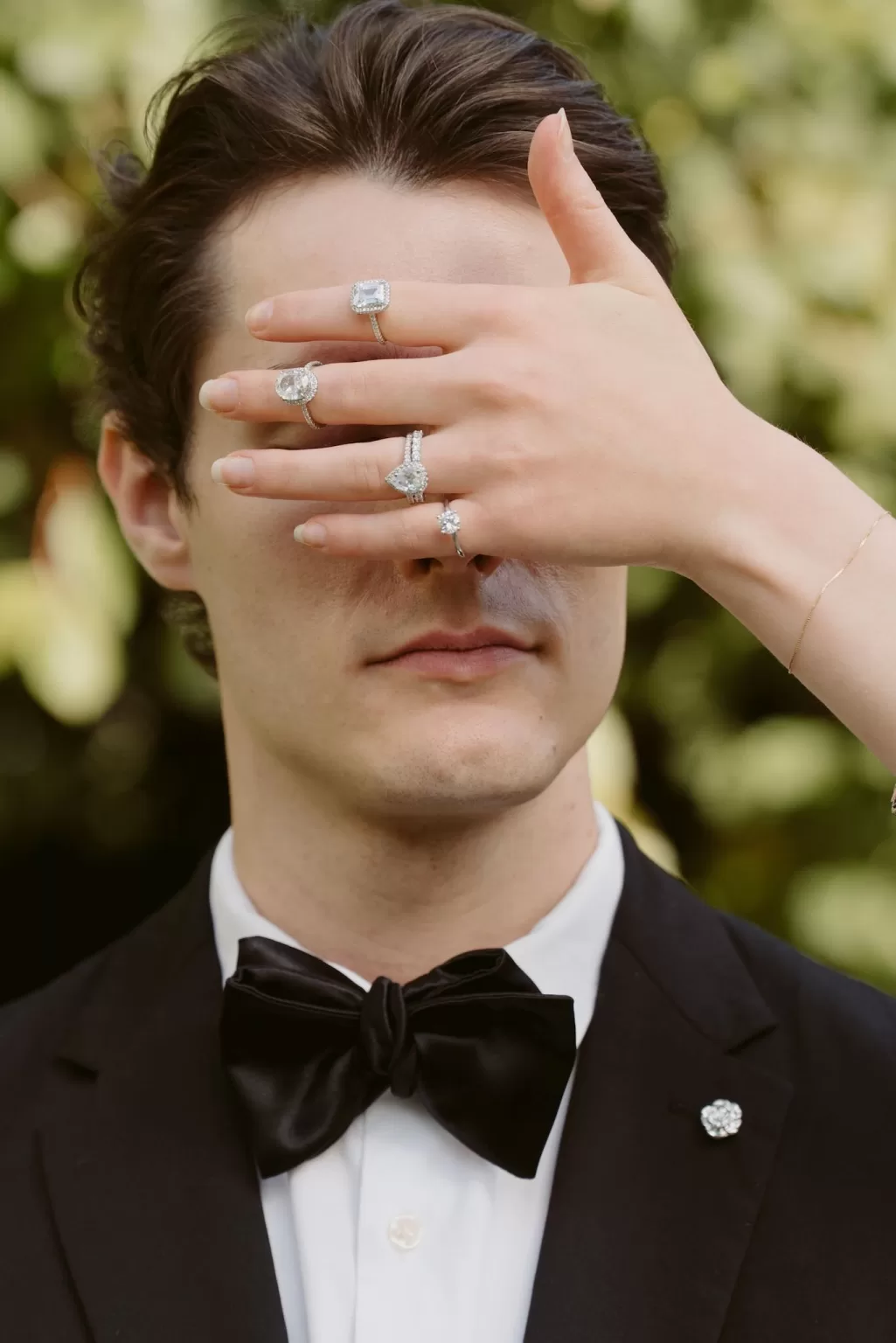 Close-up portrait featuring engagement rings held over the groom’s face, captured outdoors at Château du Prieuré d’Evecquemont.