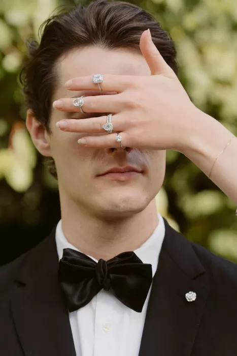 Close-up portrait featuring engagement rings held over the groom’s face, captured outdoors at Château du Prieuré d’Evecquemont.