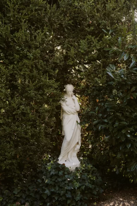 Classical garden statue framed by dense greenery at Château du Prieuré d’Evecquemont, creating a quiet, romantic atmosphere.
